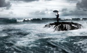 man stranded on rock with umbrella